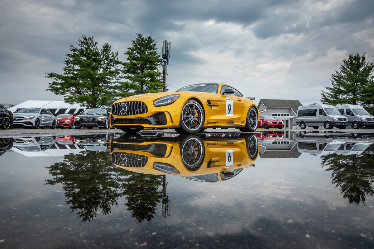 Yellow Mercedes-AMG vehicle parked at Lime Rock Park, reflecting in pool of water