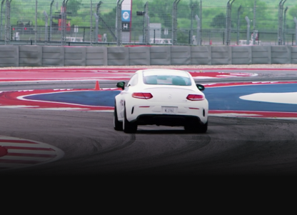 Back-view of white Mercedes-AMG vehicle racing on track