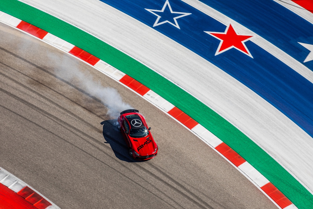 Red Mercedes-AMG vehicle drifting on Circuit of the America track, with red, white and blue stars on track