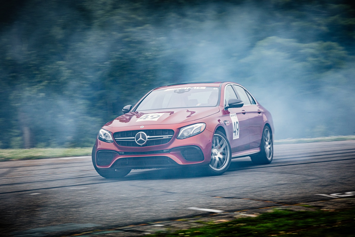 Red Mercedes-AMG vehicle drifting in cloud of smoke on Lime Rock Park track